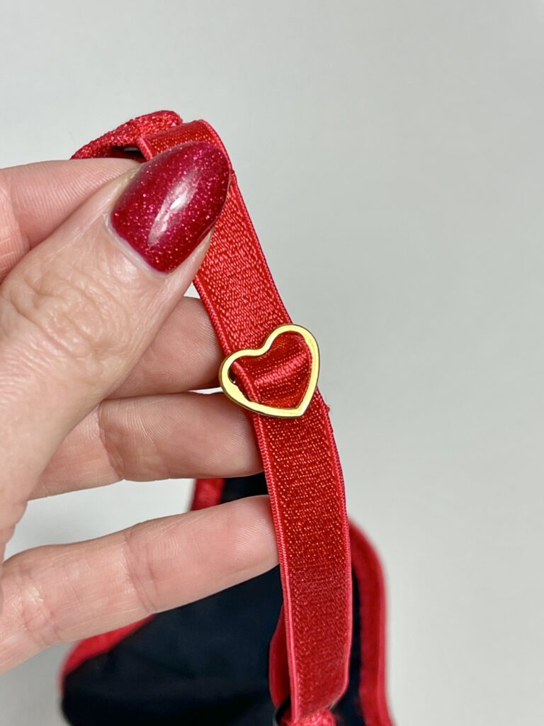 Close-up of red lingerie strap with gold heart-shaped slider, showing lingerie accessory styling tip for unique DIY designs.