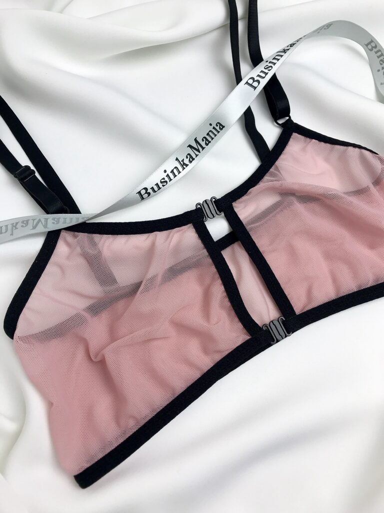 Pink mesh bralette with black elastic and front clasp closure, displayed on white fabric with BusinkaMania sewing elastic trim.
