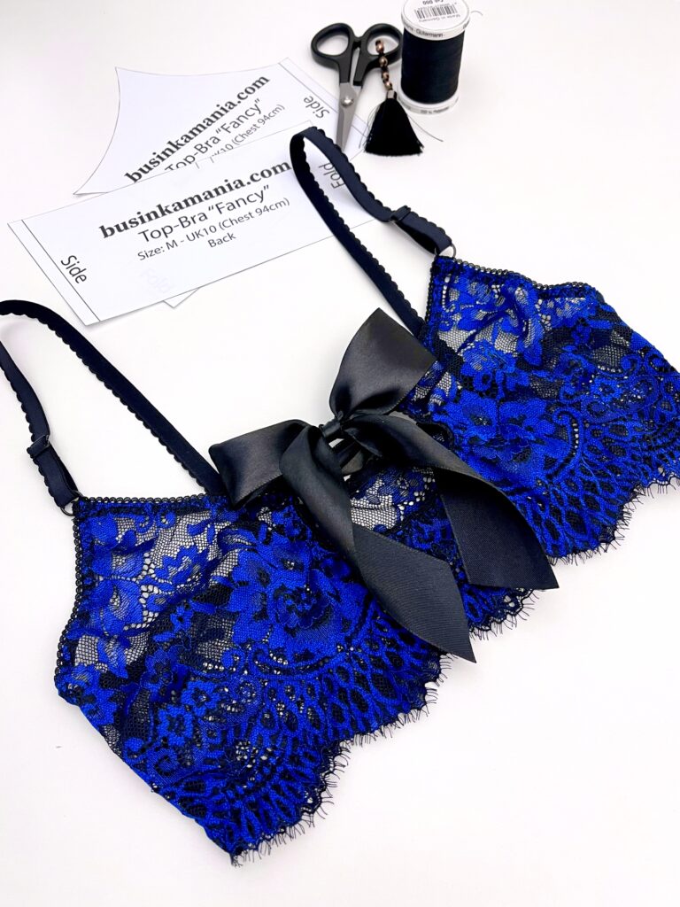 Handmade blue eyelash lace bralette with a black satin bow displayed flat.