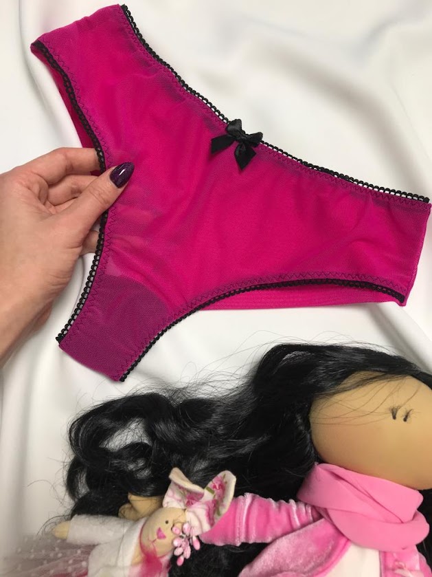 Handmade pink panties with cotton gusset lining shown on sewing table with doll, highlighting hygiene role in lingerie sewing.