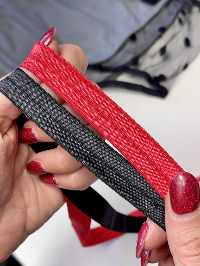 Hands holding red and black fold-over elastic, showing materials used to finish leg openings on quilted panties.