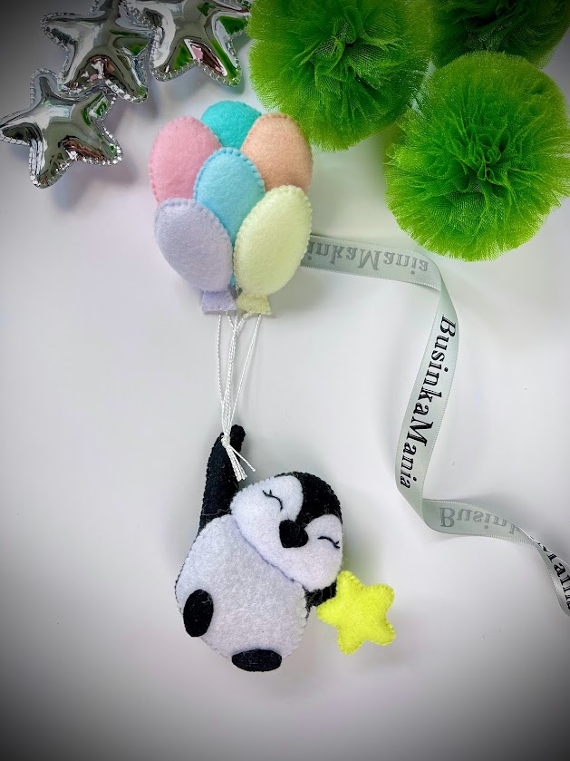 Felt penguin flying with star and colourful balloons, featuring playful hand-sewn craft made using beginner-friendly templates