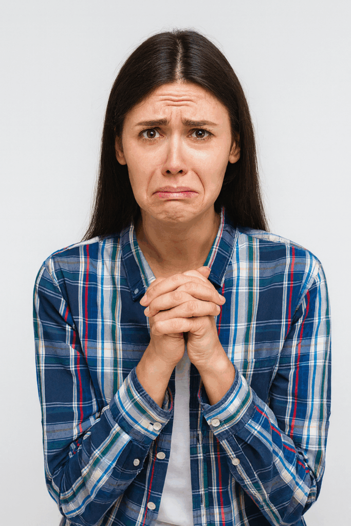Worried woman in plaid shirt clasping hands, symbolising the struggle of selling handmade creations with confidence.