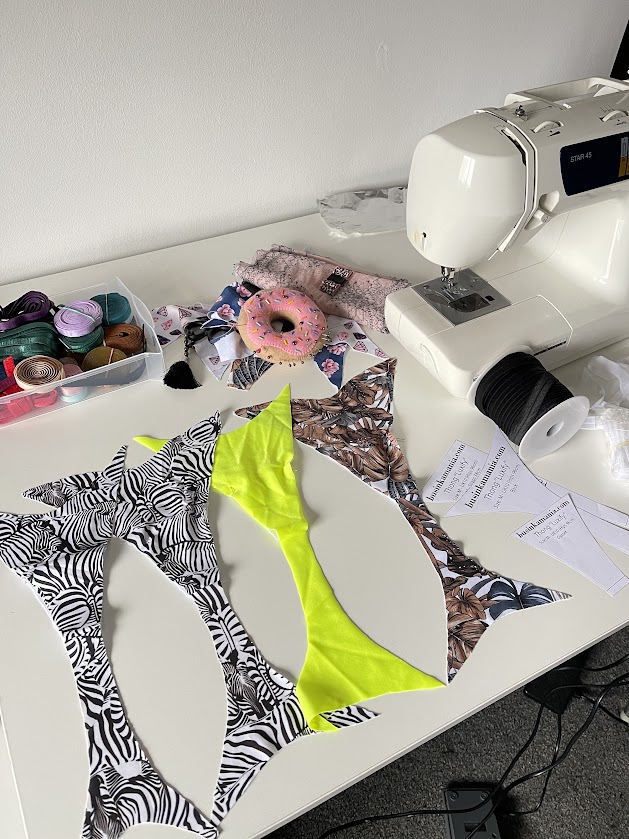 Sewing table with a sewing machine, colourful elastics, and cut panty fabric pieces ready to sew using a DIY underwear pattern