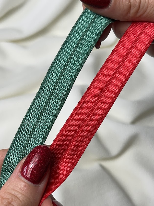 Close-up of green and red fold-over elastic used for sewing lingerie, showing the centre fold line for fabric placement