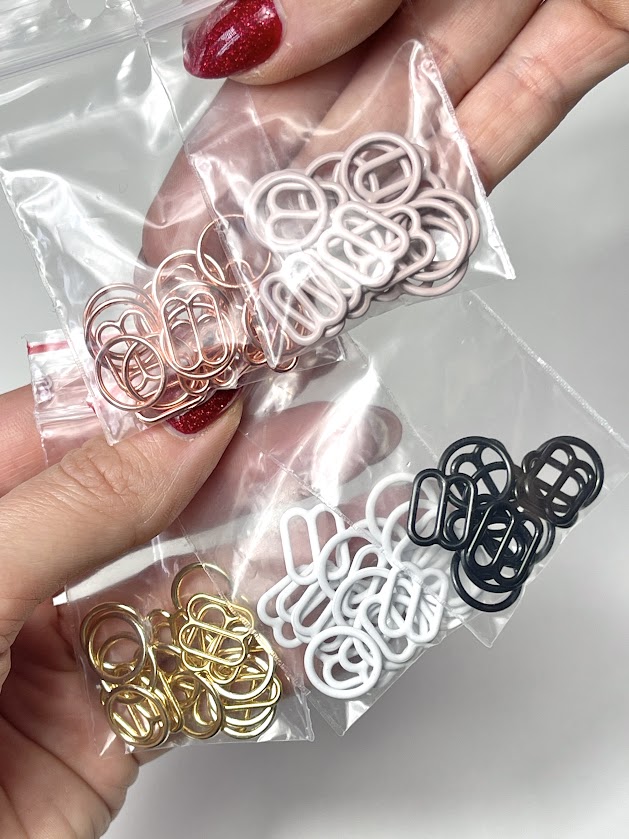Close-up of lingerie rings and sliders in gold, rose gold, black, and white used for making adjustable straps on panties