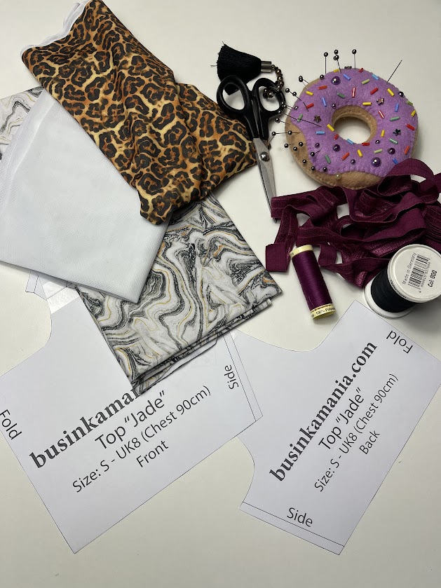 Leopard and marble stretch fabrics with sewing tools, threads, and Jade crop top pattern pieces showing material options for lingerie making.
