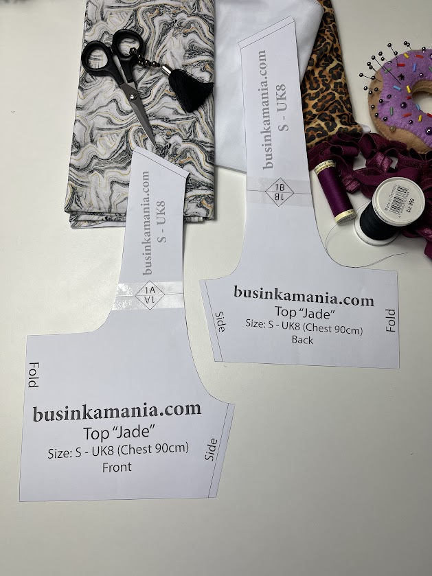 Jade crop top pattern pieces with fabrics, scissors, thread, and pin cushion prepared for cutting and sewing setup before stitching.