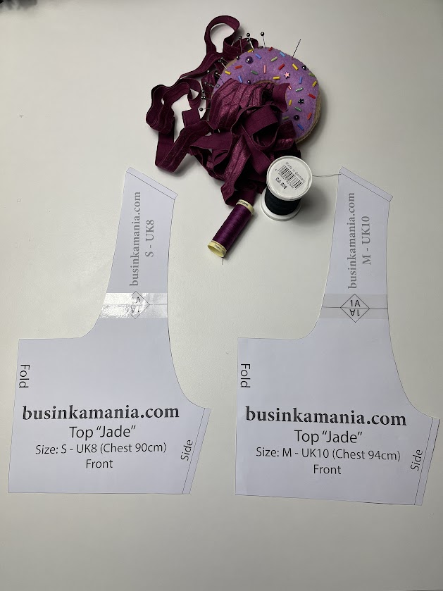 Printed Jade crop top pattern pieces with size labels, elastic trim, threads, and pin cushion showing pattern assembly preparation.