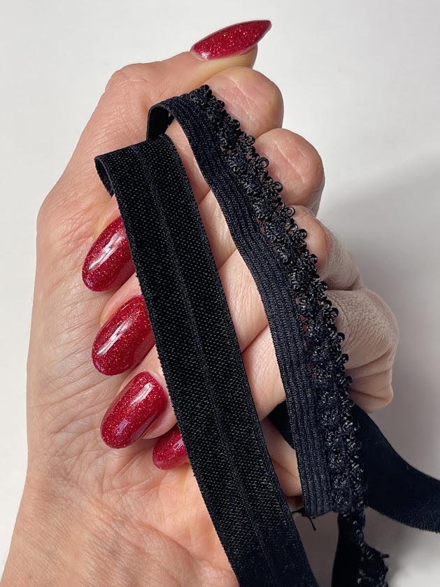 Hand holding black fold-over elastic and picot elastic, showing fabric edge options used for sewing the Jade crop top and lingerie.