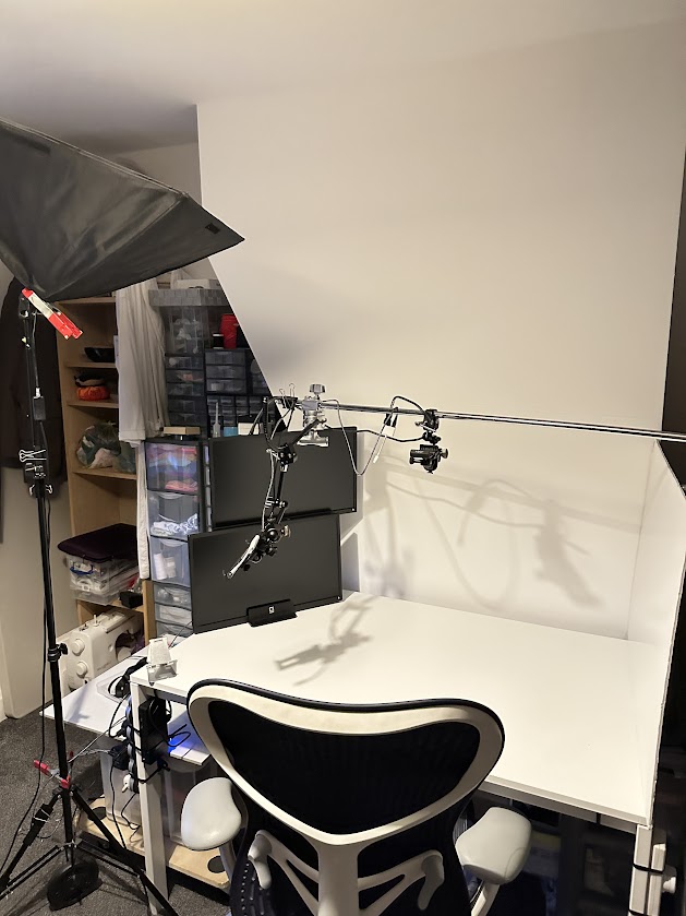 Overhead sewing recording setup in bright white room with C-stand, lighting, and tripod showing professional workspace for filming tutorials.