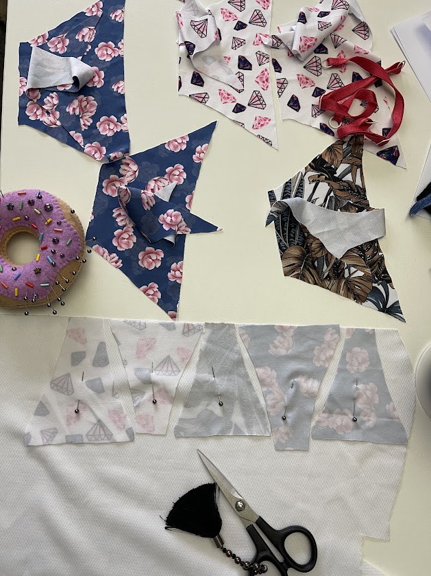 Cut fabric pieces for sewing thong panties, including front, back, and gusset sections, shown in Step 1 underwear tutorial.