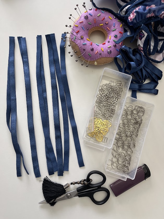 Cut elastic straps, rings, and sliders prepared for lingerie strap making, shown with sewing tools in Step 4 underwear tutorial.