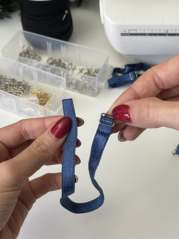 Hands holding blue elastic strap with metal slider, demonstrating how to prepare lingerie straps in Step 4 underwear tutorial.