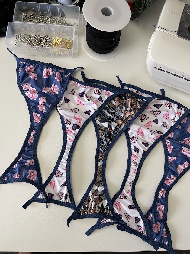 Sewing machine with handmade panties showing navy fold-over elastic stitched on edges, Step 3 of underwear sewing tutorial.