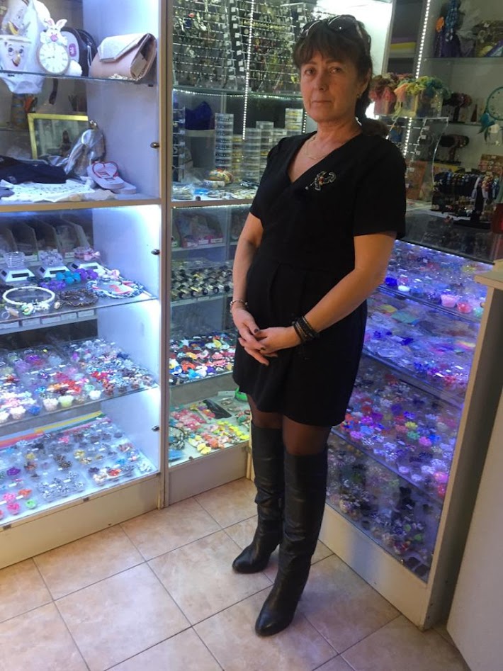 Woman in a handmade craft shop with displays of beads and accessories, showing her background in pricing handmade products.