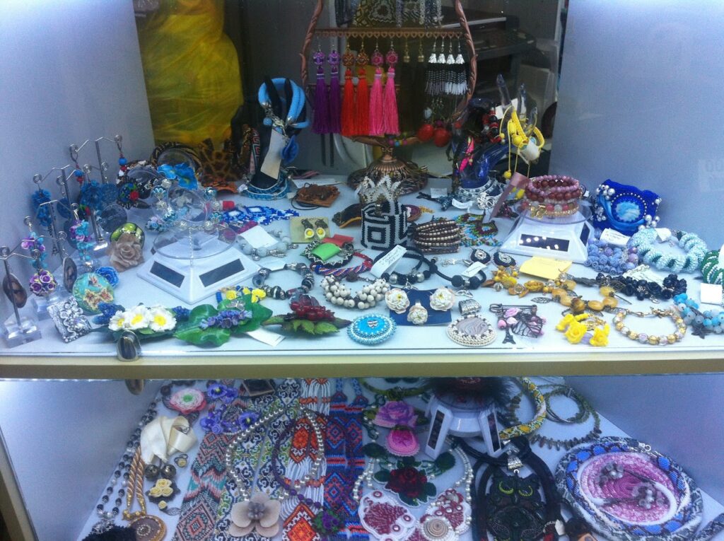 Display of handmade jewellery and accessories in a shop cabinet, representing finished creations after applying proper pricing steps.