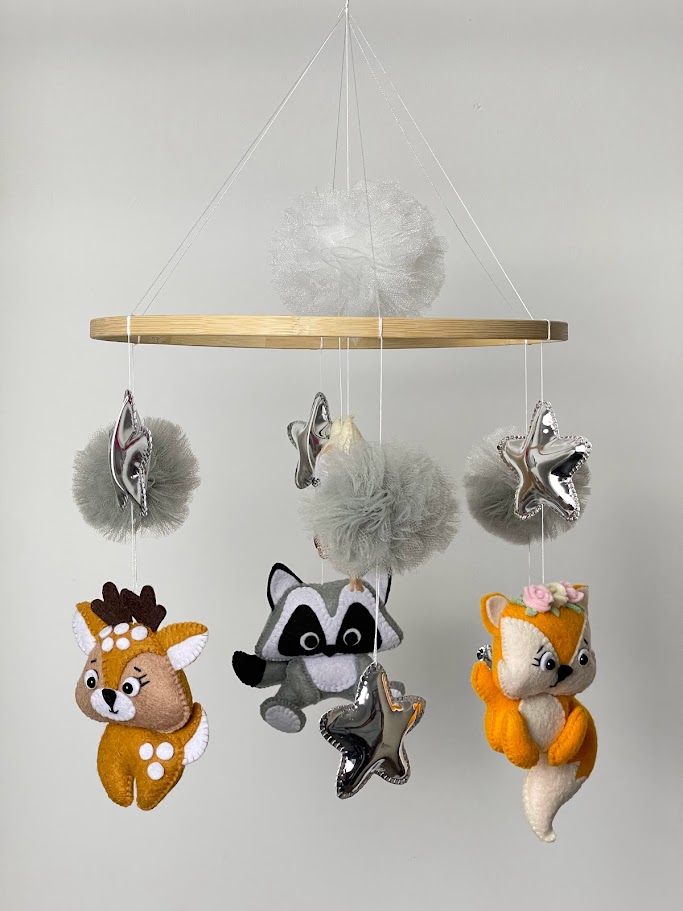 Felt cot mobile with plush animals, pom poms, and tulle rolls, showing lightweight materials used for handmade nursery mobiles