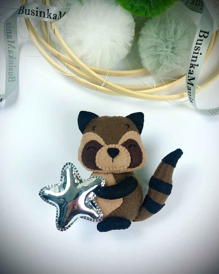 Raccoon felt plush holding mirrored leather star, example of mixed materials in DIY craft project