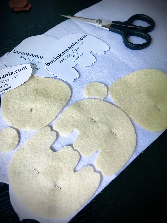 Felt toy pieces pinned together with straight head pins on soft felt for cutting identical symmetrical plush elements