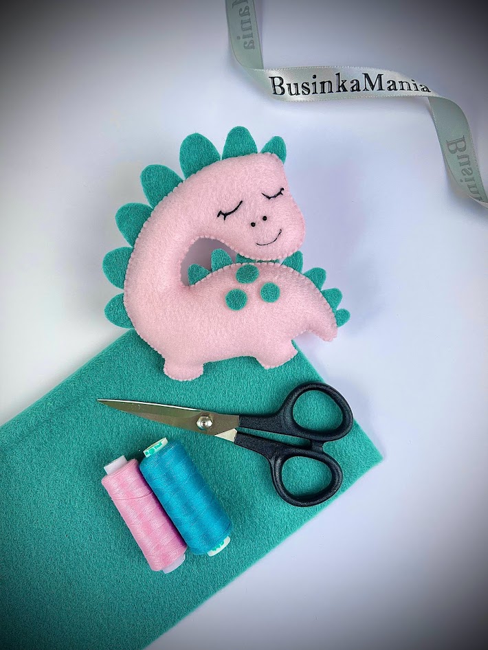 Stuffed felt dinosaur plush with chain stitch facial details, scissors and thread for felt toy sewing tutorial