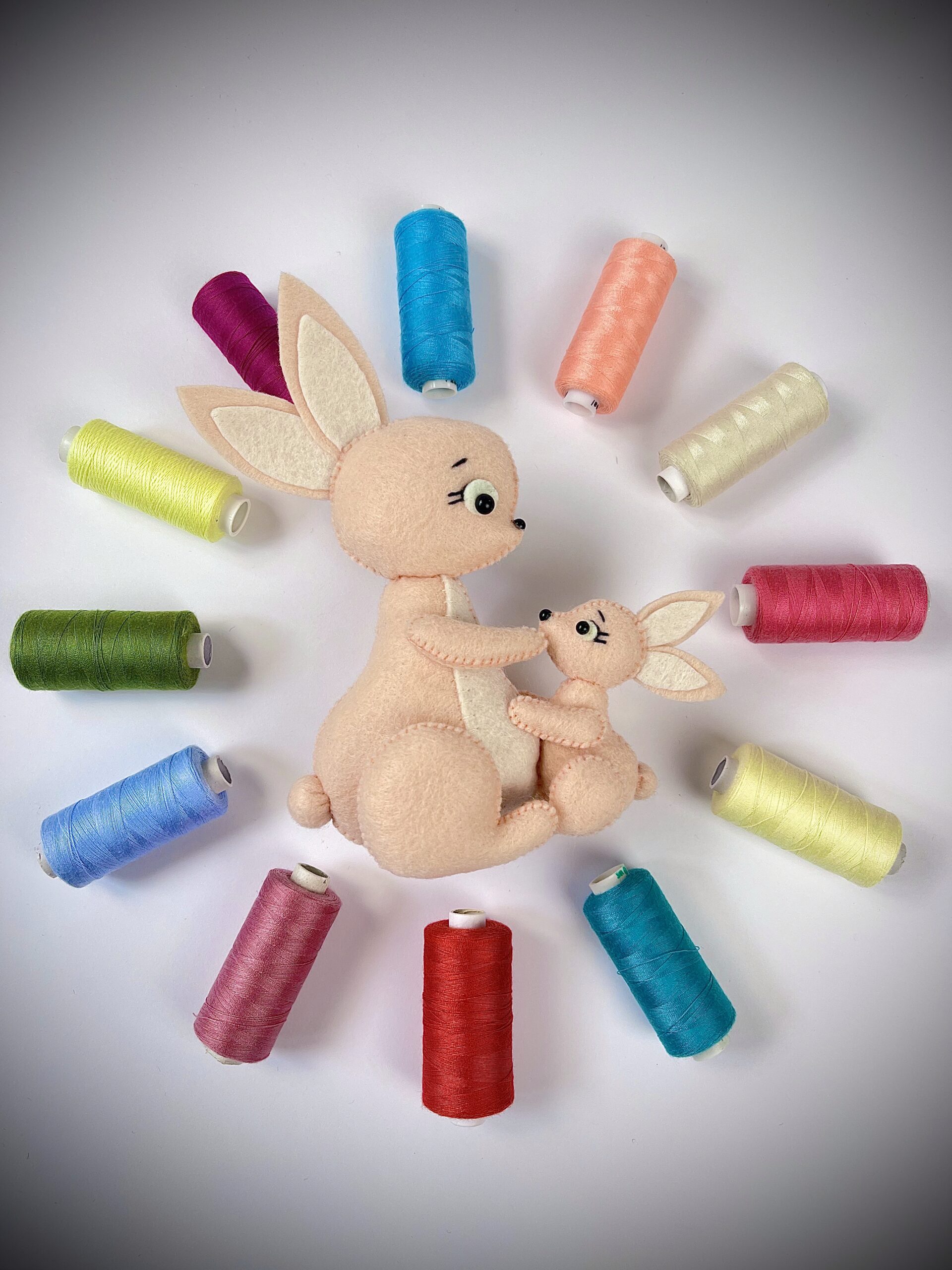 Felt bunny plush with round 3D tail surrounded by colourful sewing threads for handmade animal craft