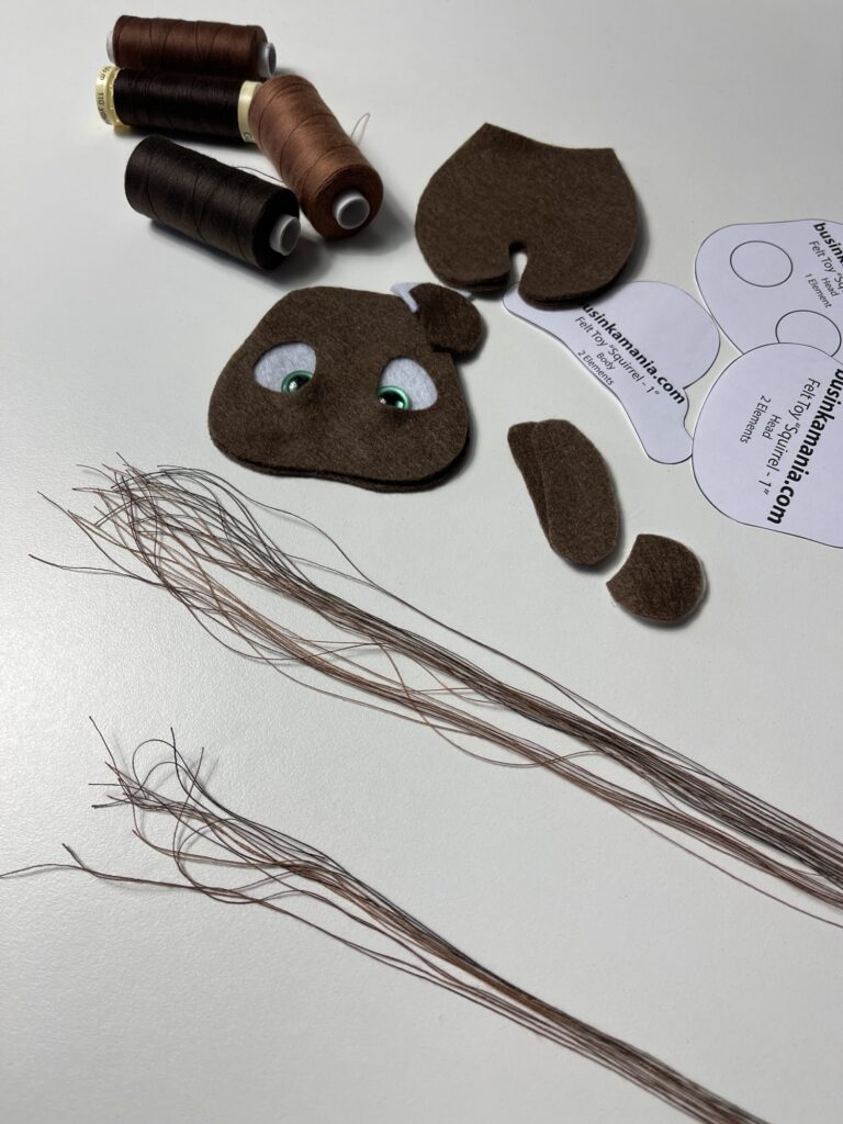 Cut polyester sewing threads to 40 cm beside felt cow pieces and pattern for braided tassel tail tutorial.