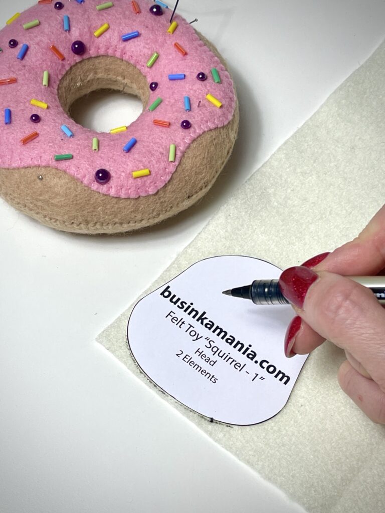 Hand outlining felt toy pattern on soft felt with black rollerball pen for precise symmetrical cutting