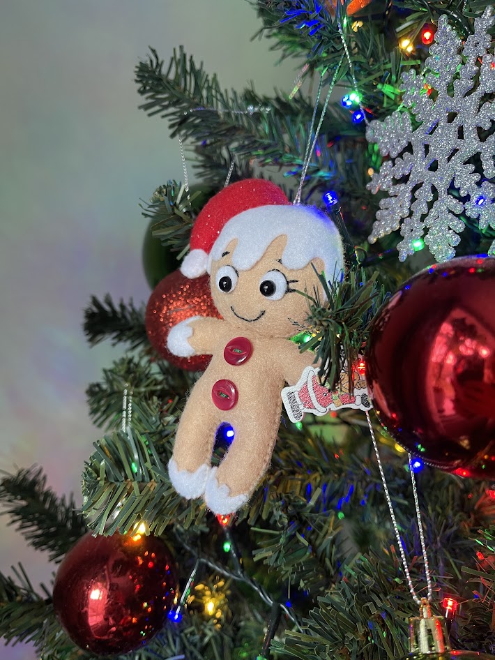 Handmade felt Christmas elf ornament hanging on a decorated tree, ready to be photographed with other plush sewing projects