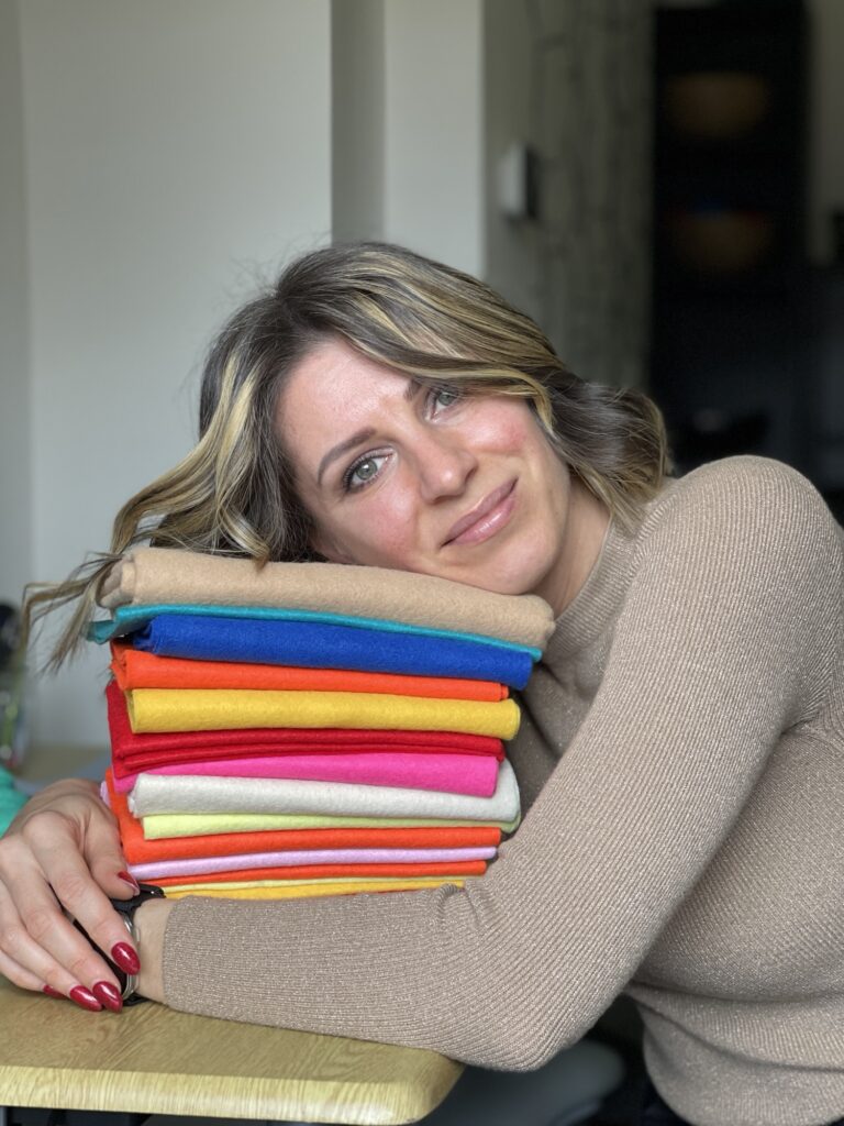 Seamstress holding colourful fabric stack, preparing to alter dog jacket for better fit in rainy weather sewing project