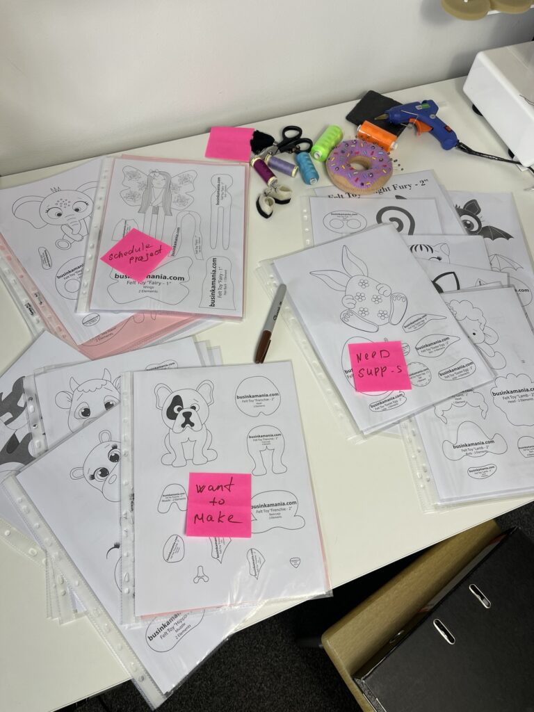 Printed felt plushie pattern pages with notes and tools laid out for cutting and sewing French bulldog plush project