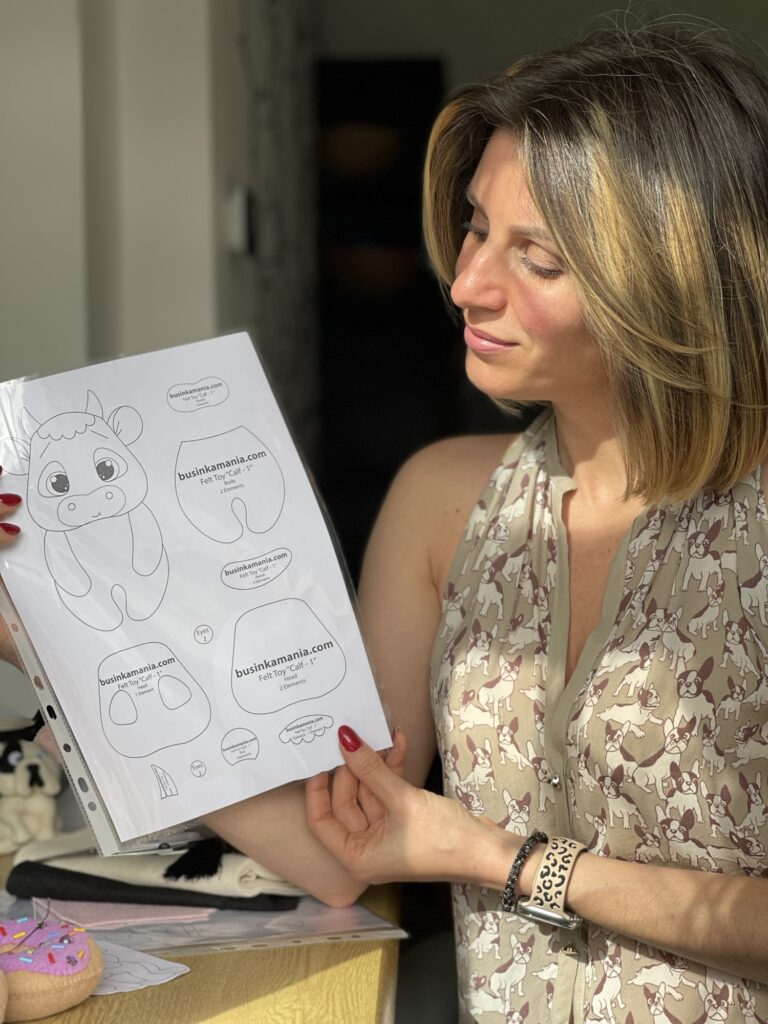 Woman holding a printable felt calf sewing pattern and planning how to finish the handmade soft felt plushie project at home