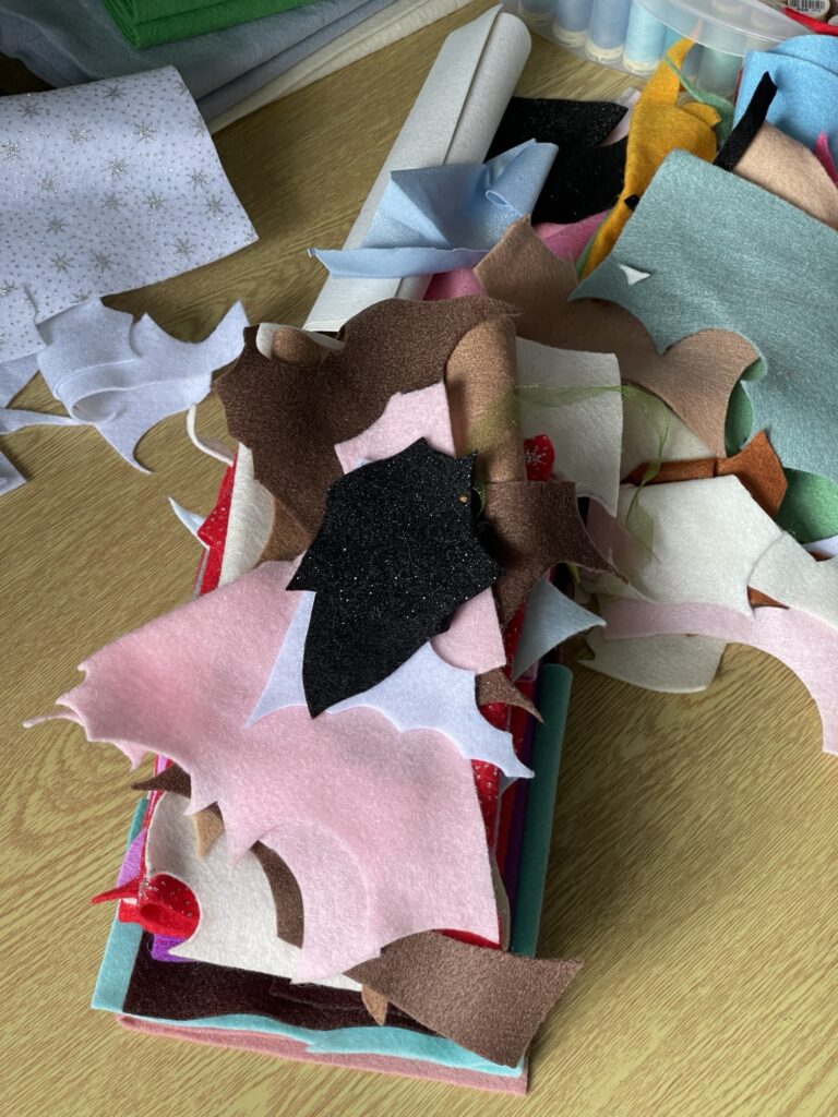Pile of assorted felt scraps in various colours showing messy craft bag before organising materials for plush toy sewing projects