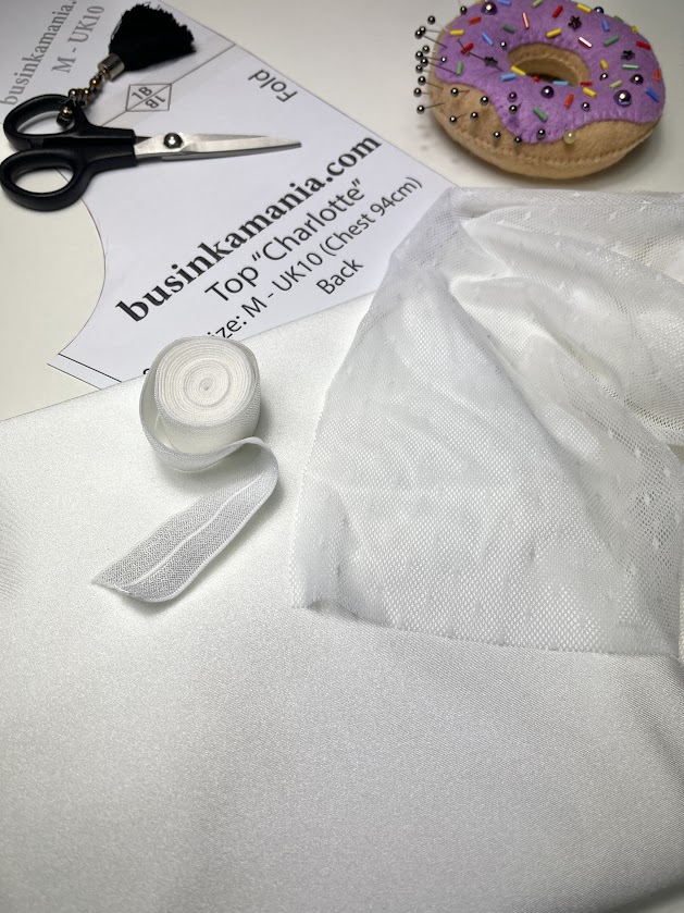 Charlotte crop top sewing setup with pattern piece, white mesh fabric, elastic roll, scissors, and pin cushion for fitting checks.