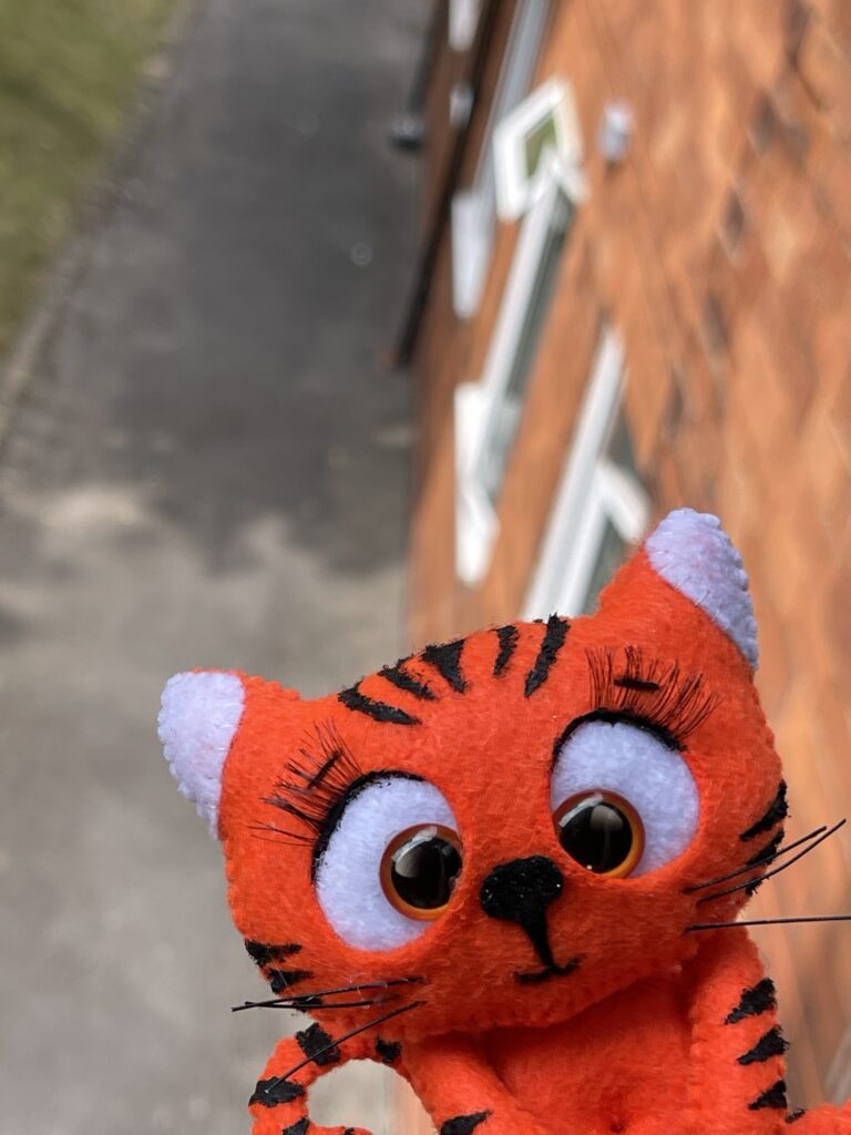 Handmade felt tiger plushie with dried black fabric paint stripes, stitched features and long eyelashes after overnight drying
