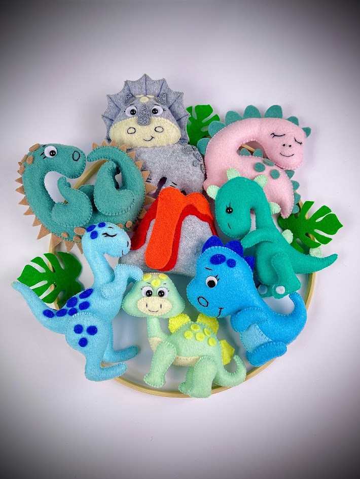 Colourful handmade felt dinosaur plushies displayed together, showcasing free felt sewing patterns for DIY craft projects